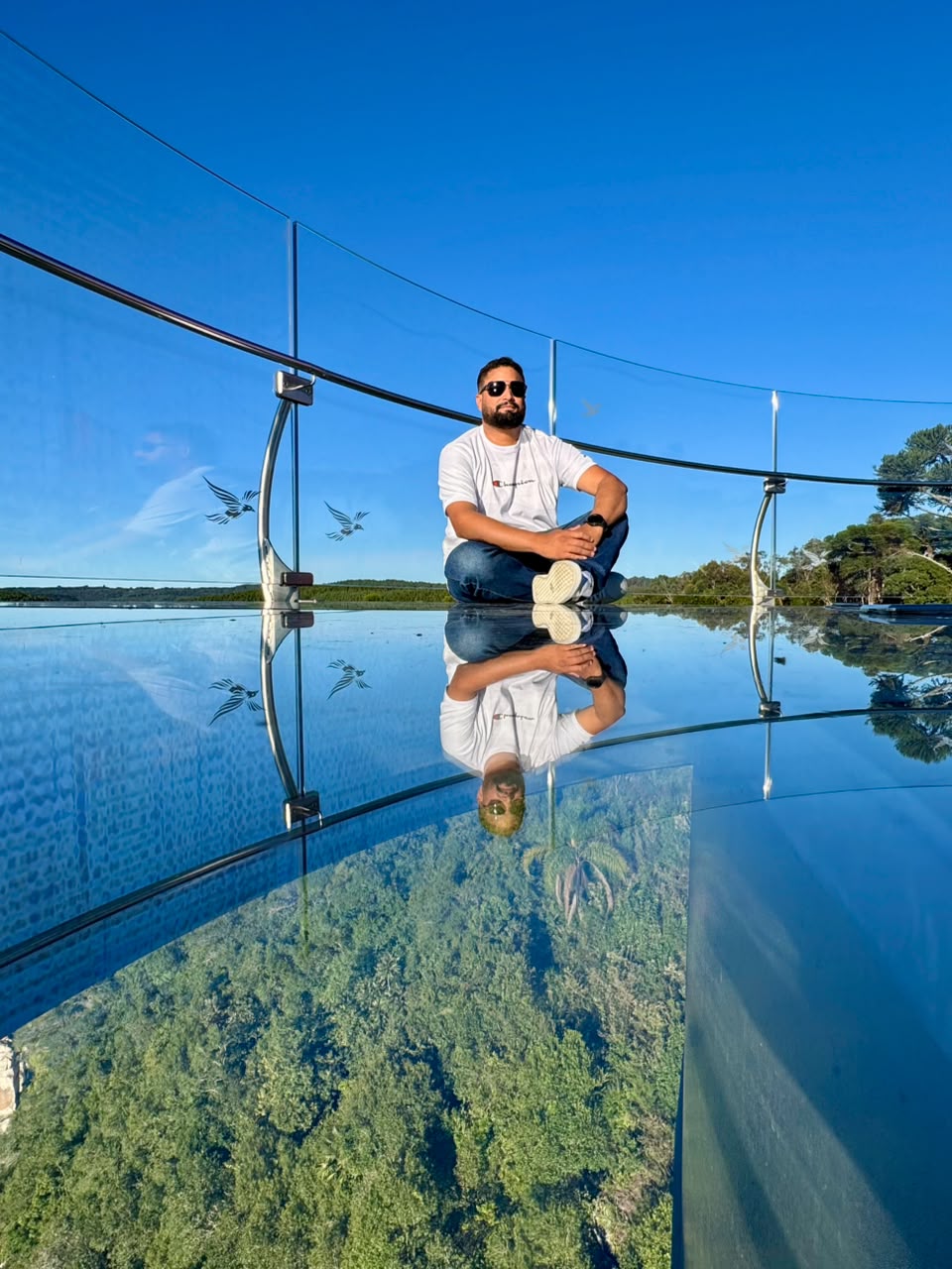 Huiatã Ribeiro em mirante de vidro com reflexo da paisagem