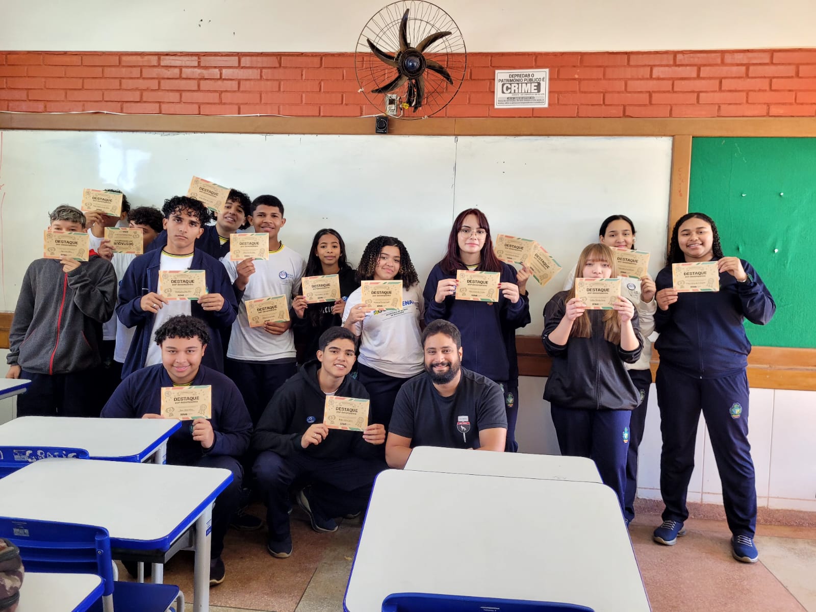 Huiatã com estudantes segurando certificados de Destaque por Desempenho em sala de aula